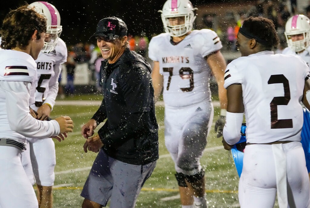 (Leah Hogsten | The Salt Lake Tribune) Lone Peak's head coach Bart Brockbank is drenched by players Alex Passey left, and Luke Hyde after the win. Lone Peak high School ends Corner Canyon's 48-game winning streak with the Knights' 41-16 win over the Chargers, Oct. 7, 2021.