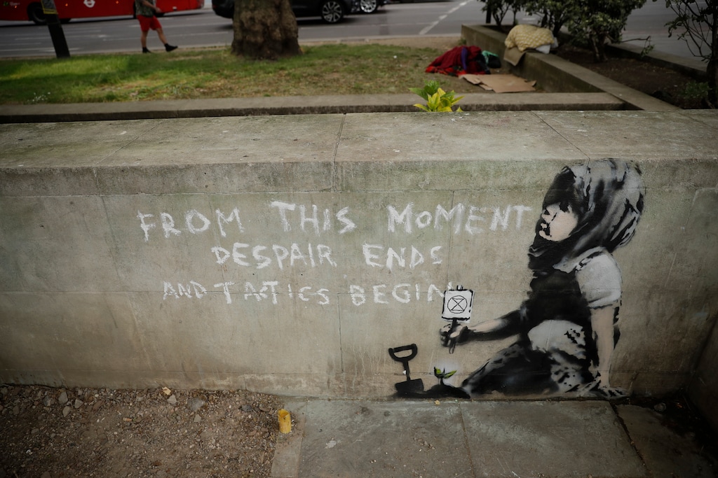 A new piece of street art that people noticed for the first time last night and is believed to be by Banksy stands on a wall where Extinction Rebellion climate protesters had set up a camp in Marble Arch, London, Friday, April 26, 2019. Extinction Rebellion ended its remaining blockades in London on Thursday evening with a closing ceremony, after disrupting the British capital for 10 days. The non-violent protest group is seeking negotiations with the government on its demand to make slowing climate change a top priority. (AP Photo/Matt Dunham)