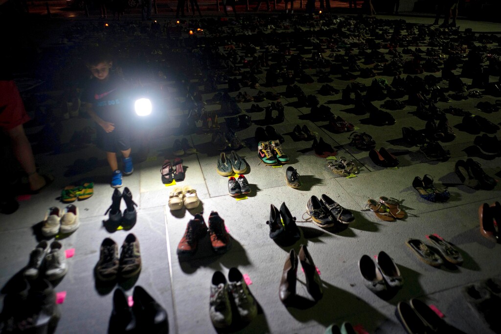(AP Photo | Ramon Espinosa, File) In this June 1, 2018 file photo, a child shines a light on hundreds of shoes at a memorial for those killed by Hurricane Maria, in front of the Puerto Rico Capitol in San Juan. Puerto Rico has conceded that Hurricane Maria killed more than 1,400 people on the island last year and not just the 64 in the official death toll.
