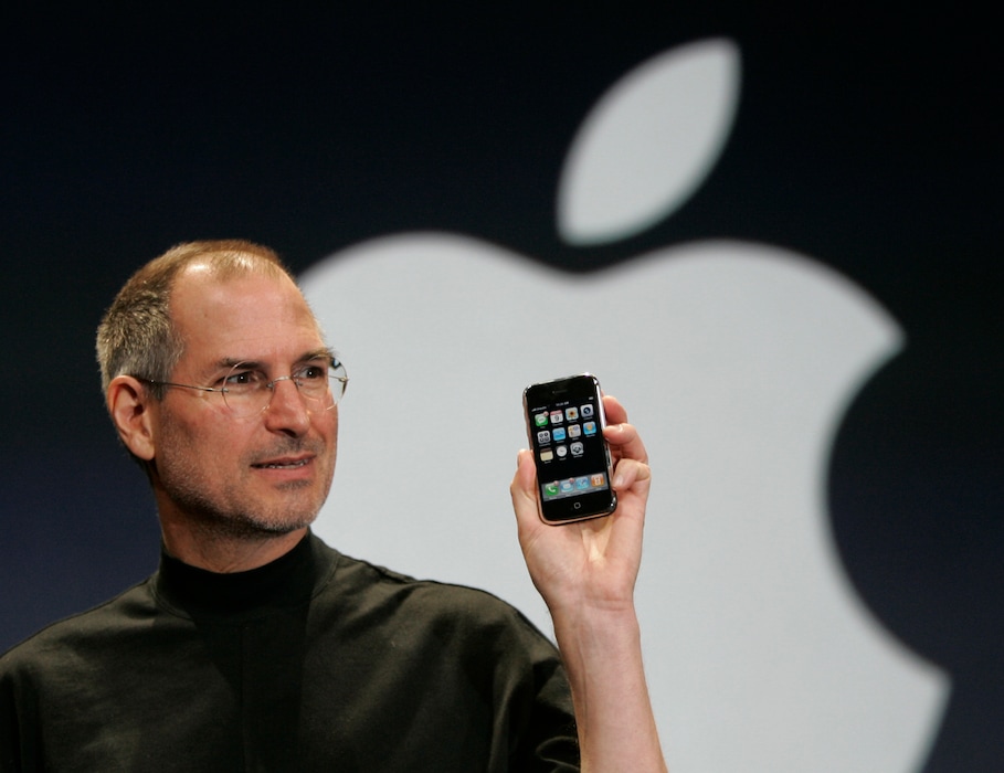 FILE - In this Jan. 9, 2007 file photo, Apple CEO Steve Jobs holds up the new iPhone during his keynote address at MacWorld Conference & Expo in San Francisco.  Apple has become the world’s first company to be valued at $1 trillion, the financial fruit of tasteful technology that has redefined society since two mavericks named Steve started the company 42 years ago.  (AP Photo/Paul Sakuma, File)