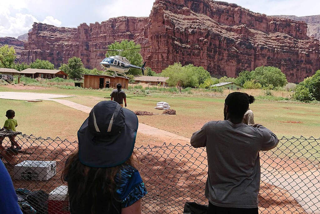 (Benji Xie | The Associated Press) This Thursday, July 12, 2018 photo released by Benji Xie shows a helicopter landing to rescue people from flooding on the Havasupai reservation in Supai, Ariz. Rescue workers were evacuating about 200 tourists Thursday who were caught in flash flooding at a popular campground on tribal land near the Grand Canyon where visitors go to see towering blue-green waterfalls.