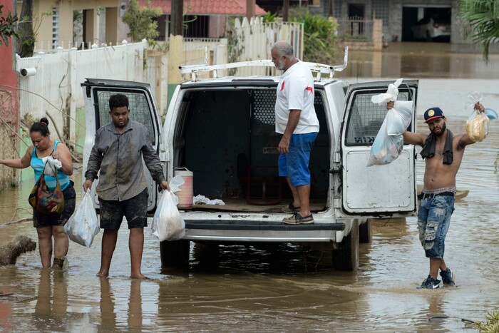 Residents manage provisions after the passing of Hurricane Maria, in Toa Baja, Puerto Rico, Friday, September 22, 2017. Because of the heavy rains brought by Maria, thousands of people were evacuated from Toa Baja after the municipal government opened the gates of the Rio La Plata Dam. (AP Photo/Carlos Giusti)