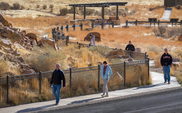 (Leah Hogsten | The Salt Lake Tribune) Visitors to the Parowan Gap, March 20, 2021 walk the path to view the many petroglyph panels. Researchers believe that the petroglyphs written into the Navajo sandstone at Parowan Gap were pecked and scratched by Native Americans who were living and farming in the Parowan Valley around 500 A.D., a time period archaeologists call the Fremont period. The Fremont Indians are closely related to the modern-day Hopi and Piute tribes and the Parowan Gap is a sacred site for both tribes.
