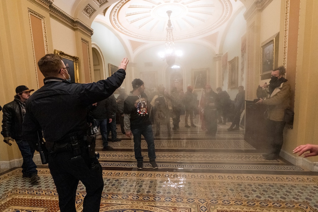 FILE - In this Jan. 6, 2021, file photo, smoke fills the walkway outside the Senate Chamber as supporters of President Donald Trump are confronted by U.S. Capitol Police officers inside the Capitol in Washington. Federal prosecutors are linking a Nevada man and a Tennessee man arrested in Las Vegas on charges arising from U.S. Capitol rioting with an Idaho man arrested earlier this month in Boise. Nathan DeGrave and Ronald Sandlin remained in federal custody Friday, Jan. 29, 2021, pending an initial court appearance Monday before a U.S. magistrate judge in Las Vegas. (AP Photo/Manuel Balce Ceneta, File)