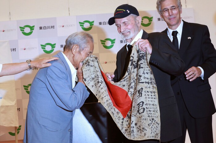 WWII veteran Marvin Strombo, center, returns Tatsuya Yasue, left, a Japanese flag with autographed messages which was owned by his brother Sadao Yasue, who was killed in the Pacific during World Work II, during a ceremony in Higashishirakawa, in central Japan's Gifu prefecture Tuesday, Aug. 15, 2017.  Strombo has returned to the fallen soldier's family the calligraphy-covered flag he took from the man's body 73 years ago.  (AP Photo/Eugene Hoshiko)