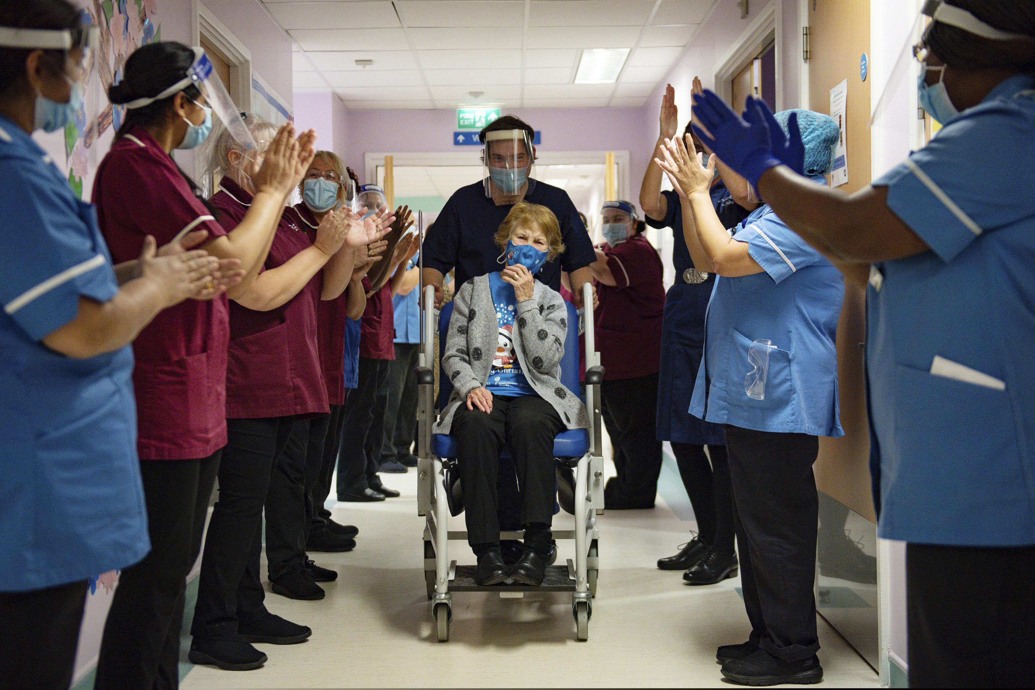 (Jacob King | AP) Margaret Keenan, 90, is applauded by staff as she returns to her ward after becoming the first patient in the UK to receive the Pfizer-BioNTech COVID-19 vaccine, at University Hospital, Coventry, England, Tuesday Dec. 8, 2020. The United Kingdom, one of the countries hardest hit by the coronavirus, is beginning its vaccination campaign, a key step toward eventually ending the pandemic.