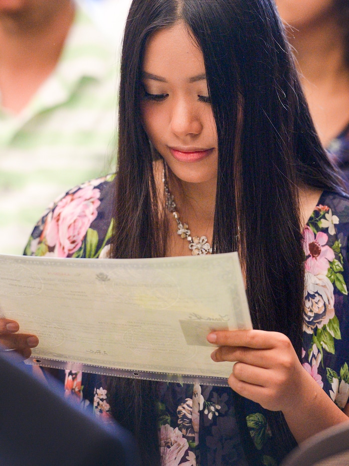Leah Hogsten | The Salt Lake Tribune Long Ching Tania Ko, 16, of Hong Kong reads her newly acquired American citizenship paperwork during a youth naturalization ceremony at the Viridian Event Center in West Jordan, Monday, August 6, 2018.