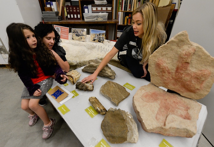 (Francisco Kjolseth  |  The Salt Lake Tribune)  Suzie Warren, left, is joined by her daughter Brekklyn, 5, as they visit a table of fossils they are allowed to touch with collections intern Savhannah Carpenter pointing out interesting details at the Natural History Museum of Utah's annual Behind the Scenes event on Saturday, Nov. 16, 2019.