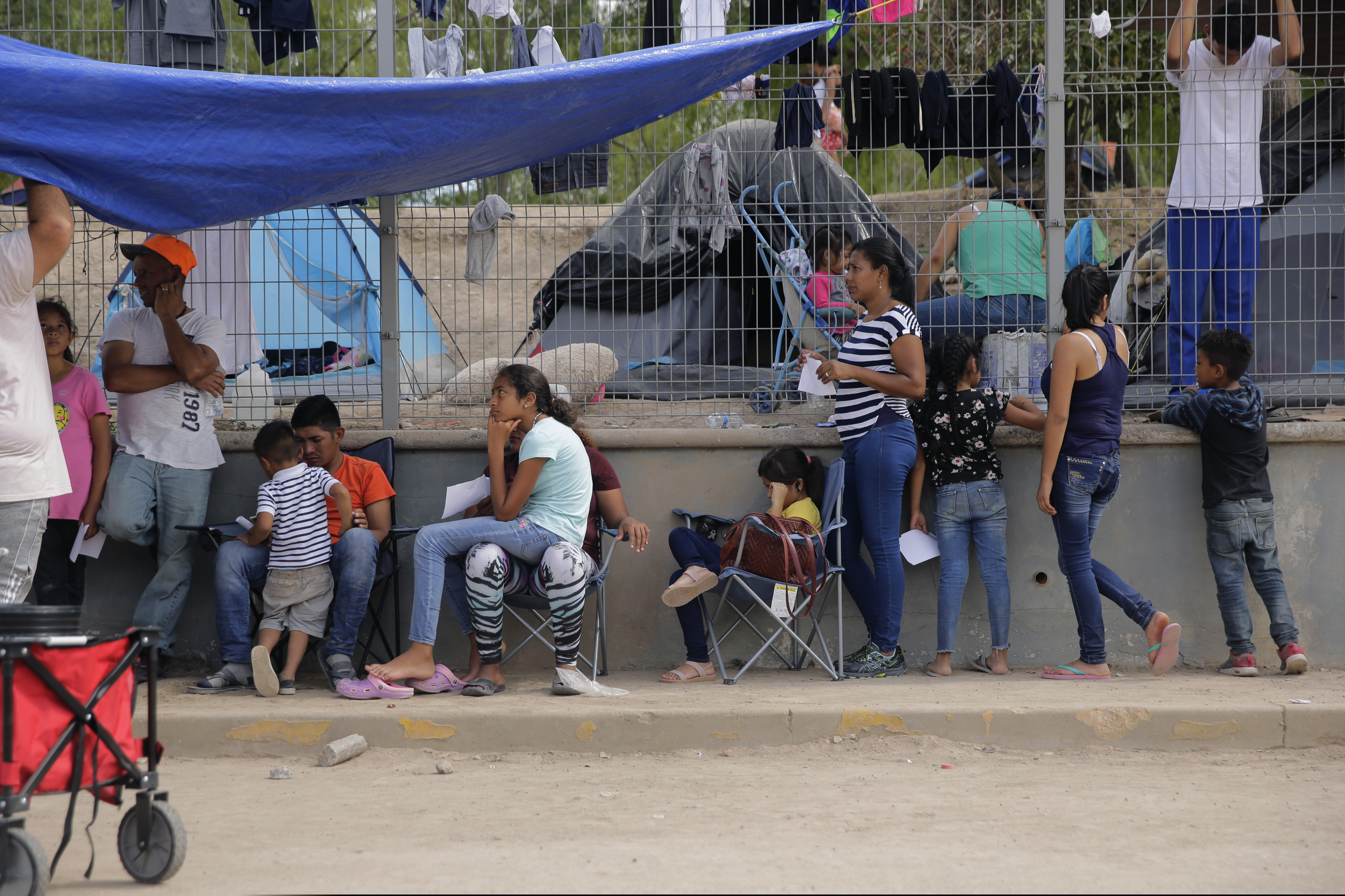 In this Tuesday, Nov. 5, 2019, photo, migrants wait to receive medical care from a sidewalk clinic at refugee camp in Matamoros, Mexico. The few doctors and nurses working in the camp are treating people including pregnant women and children with respiratory problems, skin conditions, diarrhea, and other diseases that can be linked to the camp’s unsanitary conditions. (AP Photo/Eric Gay)