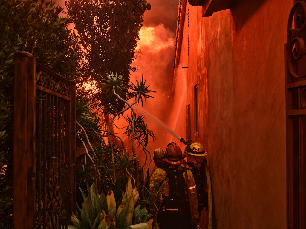 (Philip Cheung | The New York Times) Firefighters spray water in a residential area during the Pacific Palisades fire in Los Angeles, on Tuesday, Jan. 7, 2025.