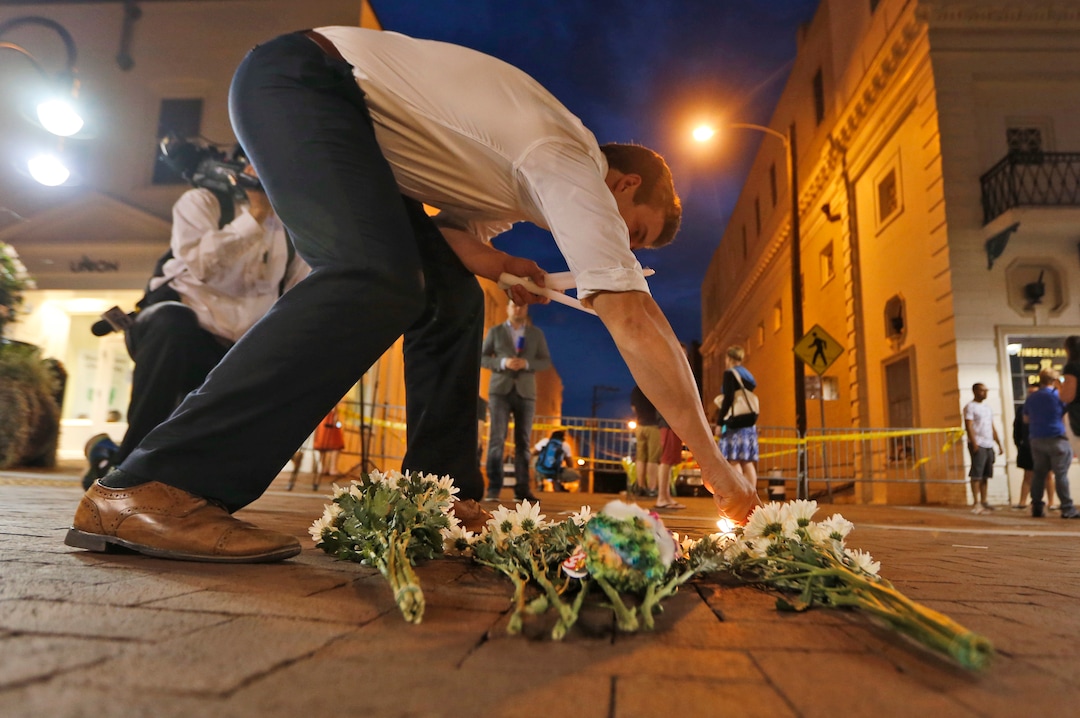 Charlottesville resident Elliot Harding lights a candle as he places flowers and a stuffed animal at a makeshift memorial for the victims after a car plowed into a crowd of people peacefully protesting a white nationalist rally earlier in the day in Charlottesville, Va., Saturday, Aug. 12, 2017. (AP Photo/Steve Helber)