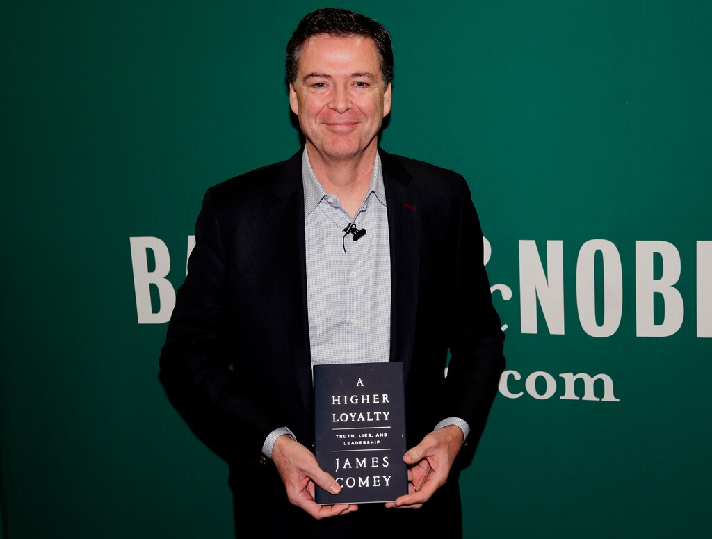 (AP Photo/Frank Franklin II) In this April 18, 2018 file photo, former FBI director James Comey poses with his book "A Higher Loyalty" at a Barnes & Noble book store in New York. Flatiron Books announced Tuesday that sales topped 600,000 copies, a number that includes print, audio and e-books. The former FBI director’s memoir has been one of the year’s most anticipated releases.