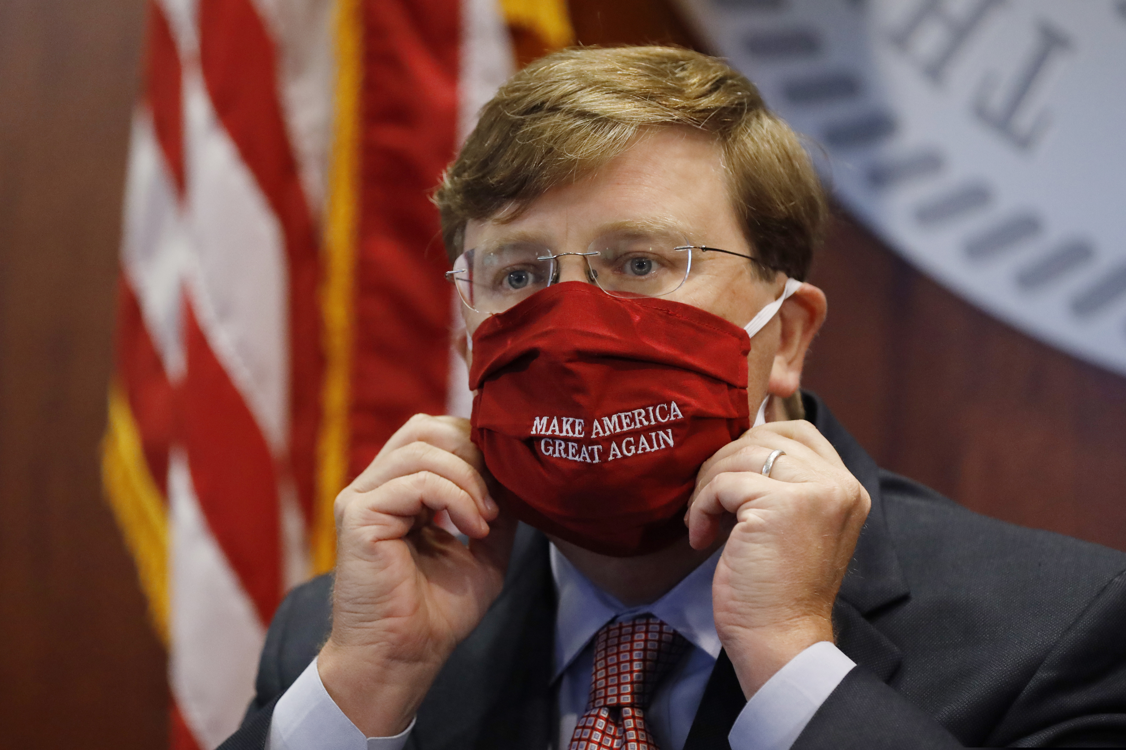Mississippi Gov. Tate Reeves adjusts his "Make America Great Again," face mask upon concluding his press briefing with members of the state's COVID-19 response team, to discuss the ongoing strategy to reduce and limit transmission, Monday, July 20, 2020, in Jackson, Miss. (AP Photo/Rogelio V. Solis)