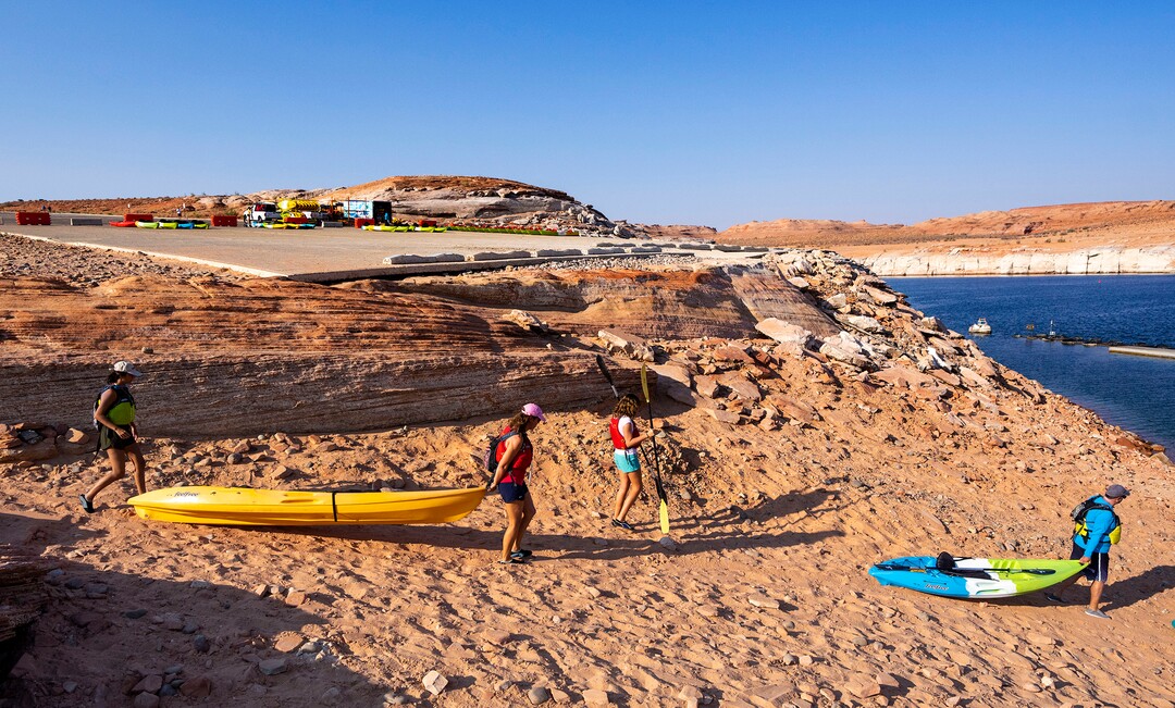 (Rick Egan | The Salt Lake Tribune) Due to the low water levels, Kayakers have to haul their kayaks another 30-50 yards to the water past the abandoned Antelope Public Launch Ramp, at Lake Powell, on Wednesday, Aug. 4, 2021. Water levels are dropping a few inches a day, which may bring an early end to kayaking on the lake in the next week or so, shortening a season that usually goes through the end of October.