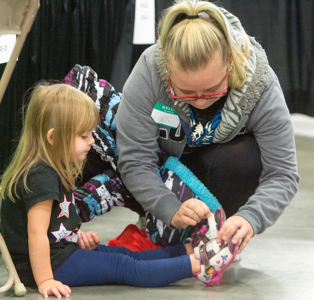 (Rick Egan  |  The Salt Lake Tribune)  Hailey Bartlett fastens the shoes for her 3-year-old daughter, Abigail Fletcher, during Project Homeless Connect on Friday, Oct. 6, 2017. The one-day event in Salt Lake City brings together community volunteers to provide services for individuals and families experiencing homelessness.