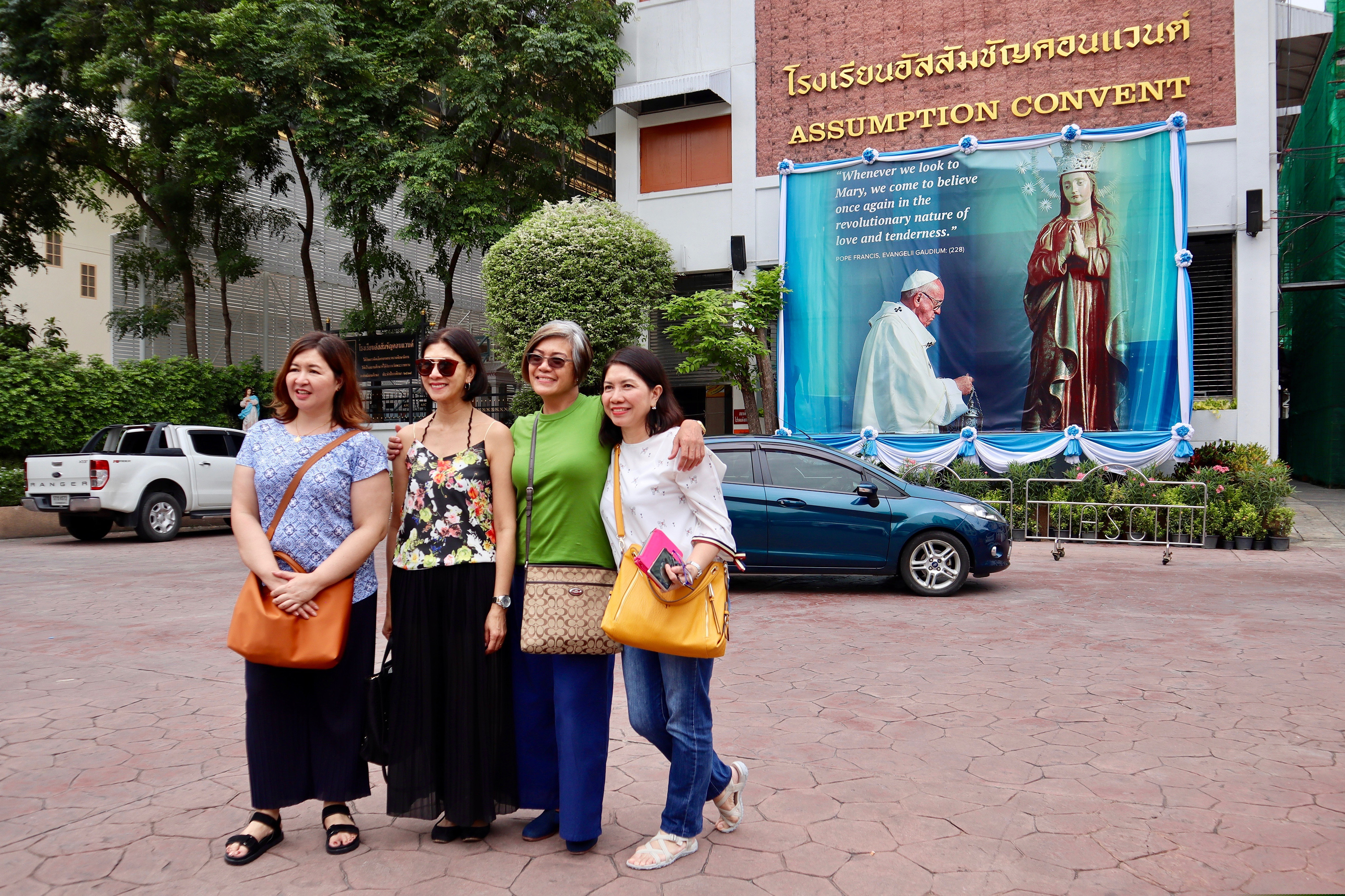 (AP Photo/Kiko Rosario) In this Sept. 8, 2019, photo, Catholic churchgoers pose in front of Pope Francis image outside a church in Bangkok, Thailand. Francis will visit Thailand and Japan on Nov. 19-26.