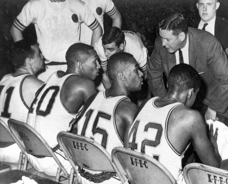 In this March 23, 1963, file photo, Loyola coach George Ireland, right, bends over to issue orders to his team that was trailing Cincinnati in the final game of the National Collegiate basketball championship at Louisville, Ky. Players, from left to right, are: John Egan, Vic Rouse, Jerry Harkness and Ron Miller. The Ramblers play Nevada on Thursday, March 22, 2018, after two thrilling wins to reach the Sweet 16, earning more wins this season than the team that won the 1963 title. (AP Photo/File)