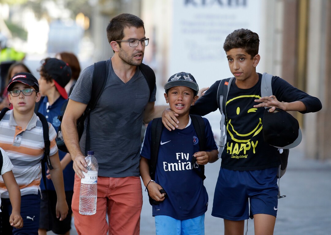 EDS NOTE : SPANISH LAW REQUIRES THAT THE FACES OF MINORS ARE MASKED IN PUBLICATIONS WITHIN SPAIN - Children, some in tears, are escorted down a road in Barcelona, Spain, Thursday, Aug. 17, 2017. Police in Barcelona say a white van has mounted a sidewalk, struck several people in the city's Las Ramblas district. (AP Photo/Manu Fernandez)