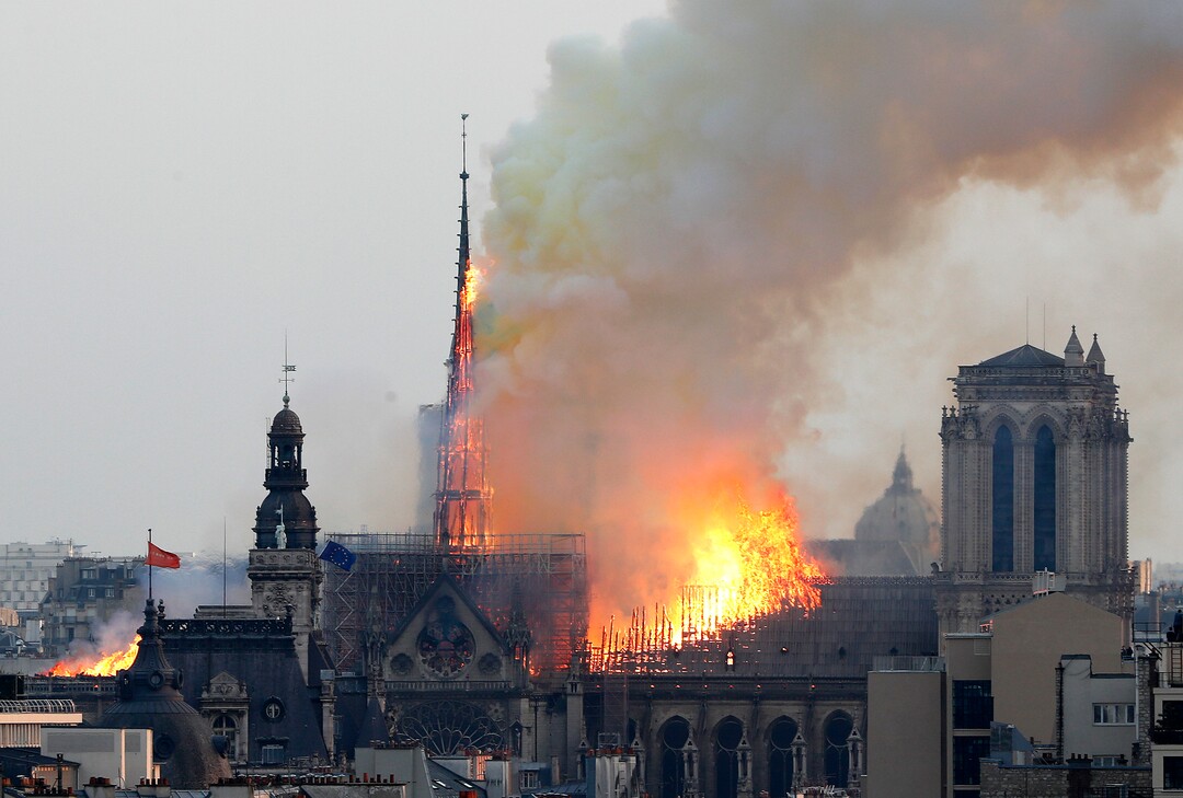 Flames rise from Notre Dame cathedral as it burns in Paris, Monday, April 15, 2019. Massive plumes of yellow brown smoke is filling the air above Notre Dame Cathedral and ash is falling on tourists and others around the island that marks the center of Paris. (AP Photo/Thibault Camus)