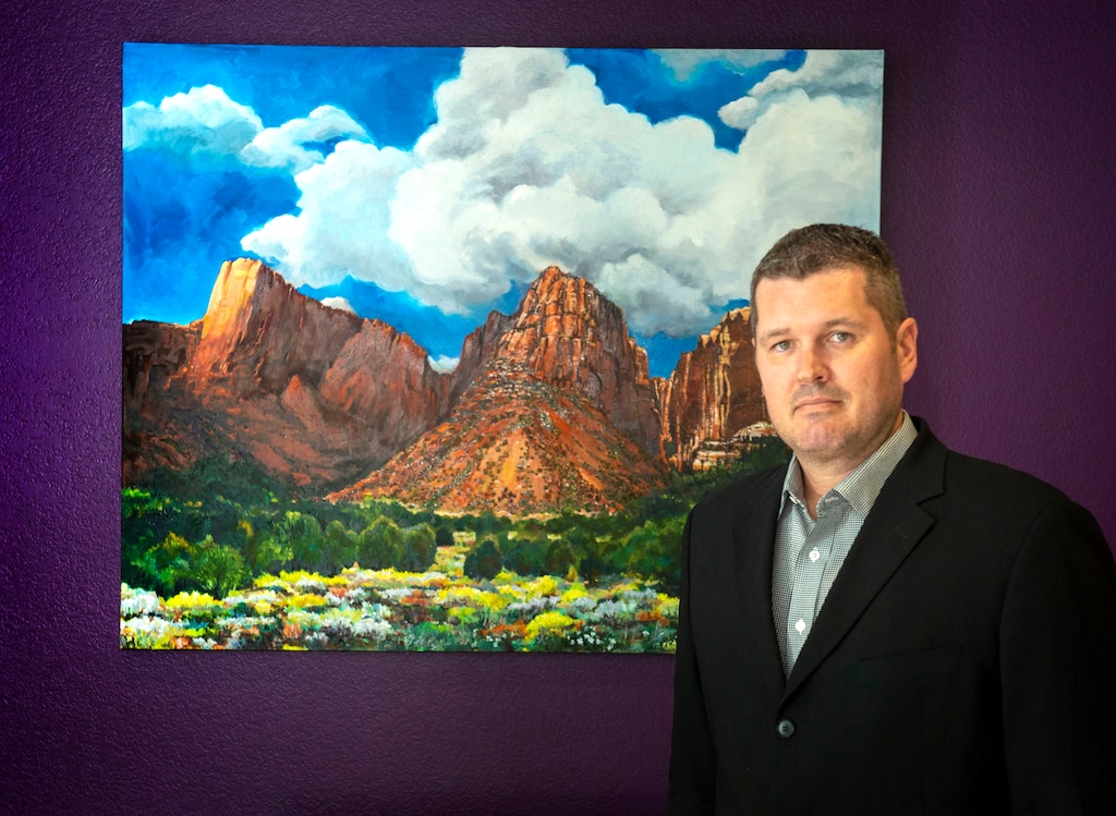 (Rick Egan  |  The Salt Lake Tribune)       Marc Fletcher stands near a piece of art his mother, Miriam Weible painted, of Maxwell Canyon, at his office in South Jordan. Thursday, May 2, 2019.