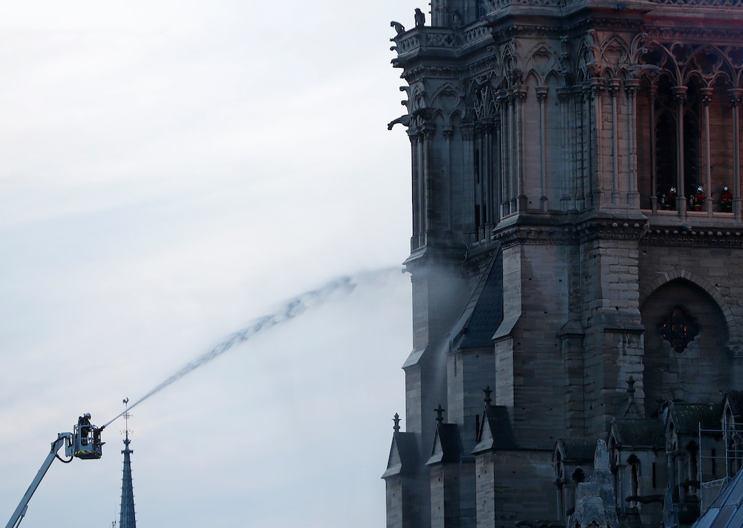 Firefighters tackle the blaze as flames and smoke rise from Notre Dame cathedral as it burns in Paris, Monday, April 15, 2019. Massive plumes of yellow brown smoke is filling the air above Notre Dame Cathedral and ash is falling on tourists and others around the island that marks the center of Paris. (AP Photo/Thibault Camus)