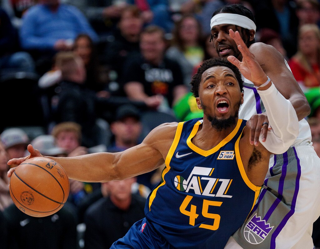 (Trent Nelson  |  The Salt Lake Tribune) Utah Jazz guard Donovan Mitchell (45) drives around Sacramento Kings forward Justin Holiday (9) as the Utah Jazz host the Sacramento Kings, NBA basketball in Salt Lake City on Saturday, March 12, 2022.