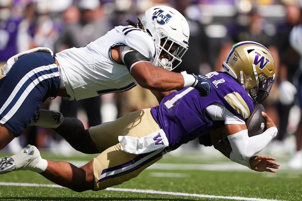 Utah State linebacker Asher Cunningham tackles Washington quarterback Demond Williams Jr., right, during the first half of an NCAA college football game Saturday, Sept. 12, 2026, in Seattle. (AP Photo/Lindsey Wasson)