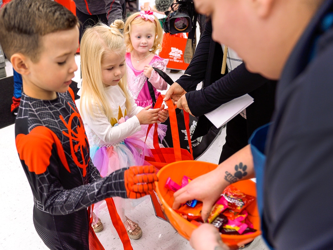 (Leah Hogsten  |  The Salt Lake Tribune)  l-r Hudson Ashcroft, 5, his sister Ella, 3, and a wide-eyed Mattie Robbins, 3, receive a handful of candy on Thursday.  Utah First Lady Jeanette Herbert handed out reflective totes to children in their Halloween costumes at Maceys grocery store and lead them around the store for trick or treating, Oct. 24, 2019 to ramp up child safety awareness this Halloween.