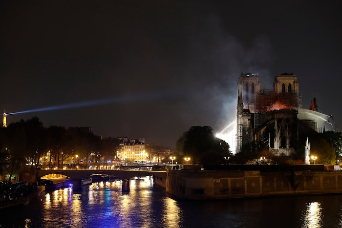 The Eiffel Tower, left, is seen while Notre Dame cathedral is burning in Paris, Monday, April 15, 2019. A catastrophic fire engulfed the upper reaches of Paris' soaring Notre Dame Cathedral as it was undergoing renovations Monday, threatening one of the greatest architectural treasures of the Western world as tourists and Parisians looked on aghast from the streets below. (AP Photo/Christophe Ena)