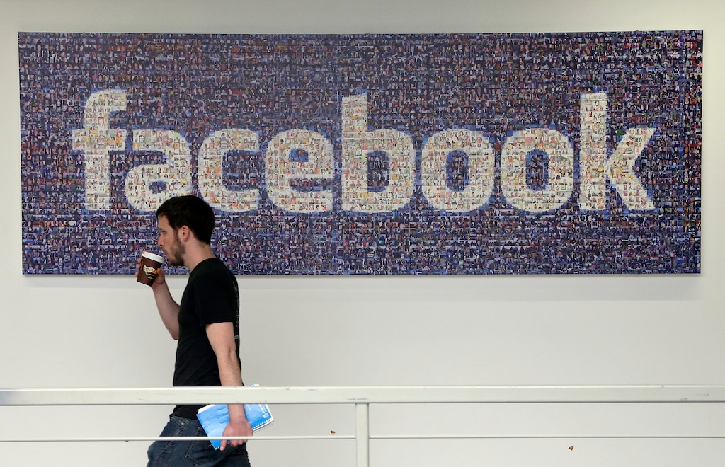 FILE - In this March 15, 2013, file photo, a man walks past a sign at Facebook headquarters in Menlo Park, California, USA. Facebook gave some companies more extensive access to users’ personal data than it has previously revealed, letting them read private messages or see the names of friends without consent, according to a New York Times report published Wednesday Dec. 19, 2018. (AP Photo/Jeff Chiu, File)