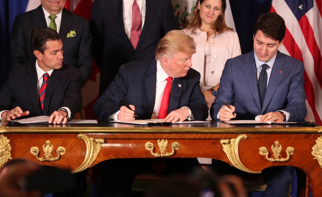 President Donald Trump, center, looks over at Canada's Prime Minister Justin Trudeau's document as they and Mexico's President Enrique Pena Nieto sign a new United States-Mexico-Canada Agreement that is replacing the NAFTA trade deal, during a ceremony at a hotel before the start of the G20 summit in Buenos Aires, Argentina, Friday, Nov. 30, 2018. The USMCA, as Trump refers to it, must still be approved by lawmakers in all three countries. (AP Photo/Martin Mejia)