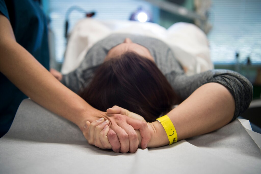(Carolyn Van Houten | The Washington Post) An abortion doula named Grace clasps hands with a patient during her procedure at a Virginia abortion clinic.