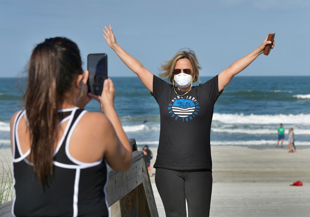 Delcia Dias, left, and Monica Dias celebrate the beaches opening on a limited basis, Friday, April 17, 2020 on Jacksonville Beach, Fla. Gov. Ron DeSantis has given the green light for some beaches and parks to reopen if it can be done safely after being closed because of the coronavirus. DeSantis' announcement on Friday came as north Florida beaches became among the first to allow beach-goers to return since the closures. (Will Dickey/The Florida Times-Union via AP)