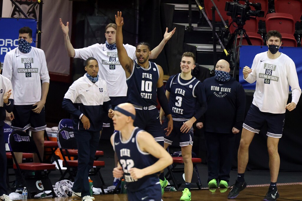 The Utah State bench reacts as Utah State guard Brock Miller (22) sinks a 3-point shot during the first half of an NCAA college basketball game against San Diego State in the championship of the Mountain West Conference men's tournament Saturday, March 13, 2021, in Las Vegas. (AP Photo/Isaac Brekken)