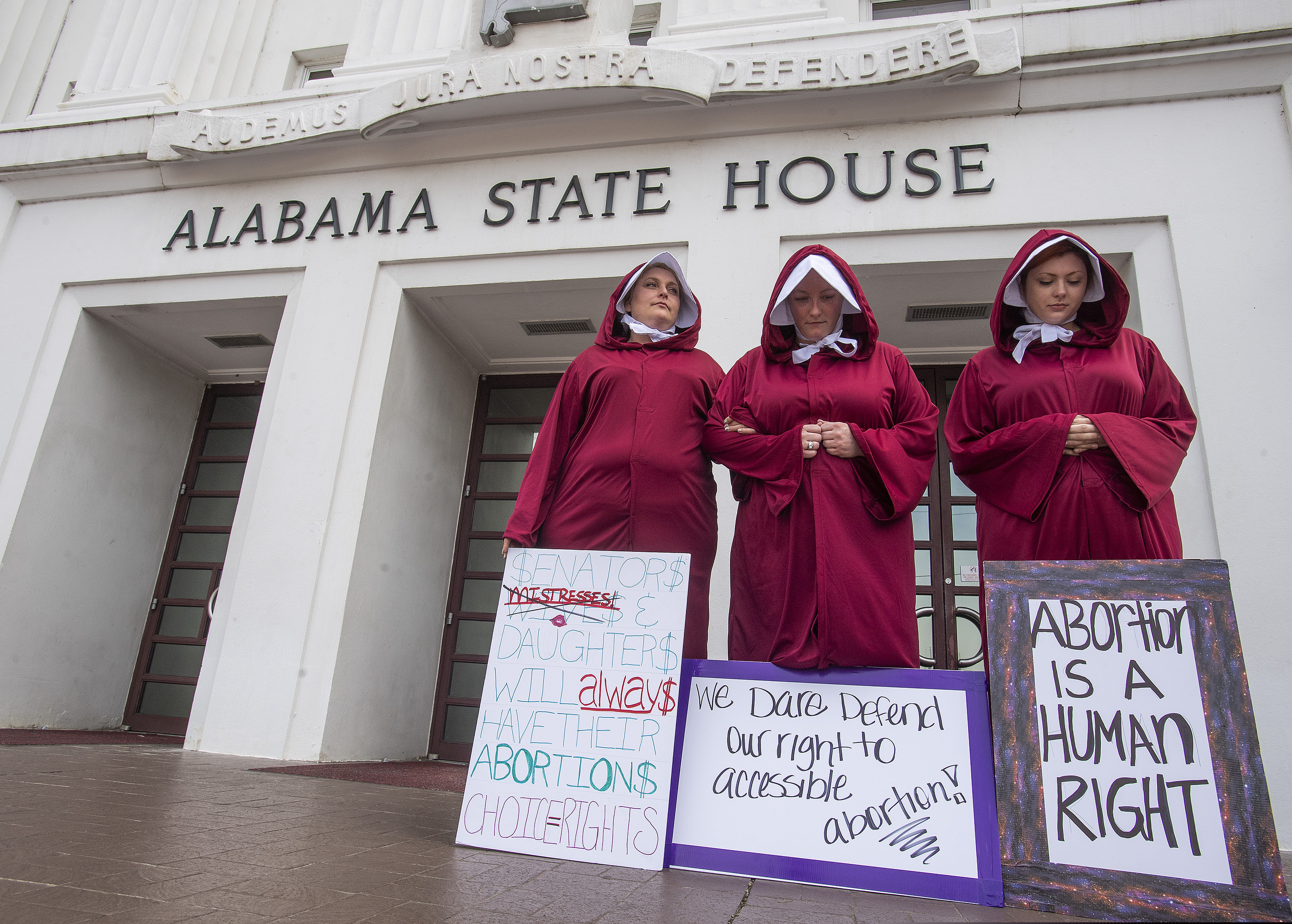 FILE - In this Wednesday April 17, 2019 file photo, Bianca Cameron-Schwiesow, from left, Kari Crowe and Margeaux Hardline, dressed as handmaids, take part in a protest against HB314, the abortion ban bill, at the Alabama State House in Montgomery, Ala. An attempt to outlaw abortion in Alabama is headed to a committee vote in the Alabama Senate. The Senate Judiciary Committee will vote Wednesday morning, May 8, 2019, on the bill following a public hearing. (Mickey Welsh/The Montgomery Advertiser via AP, File)