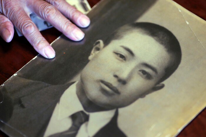 In this Aug. 14, 2017 photo, Tatsuya Yasue, 89-year-old farmer, shows a photo of his brother Sadao Yasue, who fell in battle during the war in Pacific more than 70 years ago, in Higashishirakawa, in central Japan's Gifu prefecture. Former U.S. Marine Marvin Strombo will returns Sadao's calligraphy-covered flag he took from the fallen Japanese soldier 73 years ago. (AP Photo/Eugene Hoshiko)