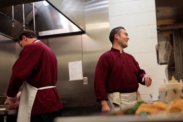 In this photo taken Jan. 26, 2018, Michael Hall speaks with highway patrol officers as they go through the line in the Code 7 Cafe in the Utah County Jail in Spanish Fork, Utah. The Utah County Jail Culinary Arts program utilizes inmates labor in the commercial kitchen. (Evan Cobb/The Daily Herald via AP)