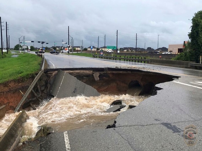 (Photo courtesy of the Rosenberg Police Department via AP) In this photo provided by the Rosenberg Police Department water rushes from a large sinkhole on Highway FM 762 in Rosenberg, Texas, near Houston, Sunday, Aug. 27, 2017. Police say the sinkhole has opened on the Texas highway as Tropical Storm Harvey dumps more rain on the region.