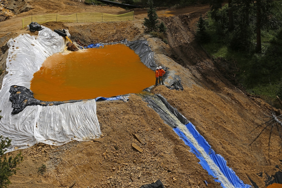 In a Monday, Aug. 10, 2015 photo, environmental restoration employees work at a temporary water treatment holding facility at the Gold King Mine north of Silverton, Colo.  Local officials in towns downstream from where millions of gallons of mine waste spilled into the San Juan River are demanding answers about possible long-term threats to the water supply. The 3 million gallons of mine waste included high concentrations of arsenic, lead and other heavy metals. Workers with the EPA accidentally unleashed the spill Wednesday as they inspected the abandoned mine site. (Jon Austria/The Daily Times via AP)