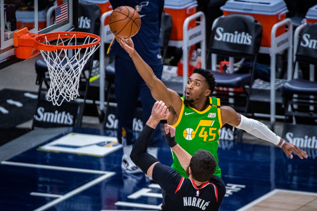 Utah Jazz guard Donovan Mitchell (45) lays the ball up while guarded by Portland Trail Blazers center Jusuf Nurkic (27) during the first half of an NBA basketball game Thursday, April 8, 2021, in Salt Lake City. (AP Photo/Isaac Hale)