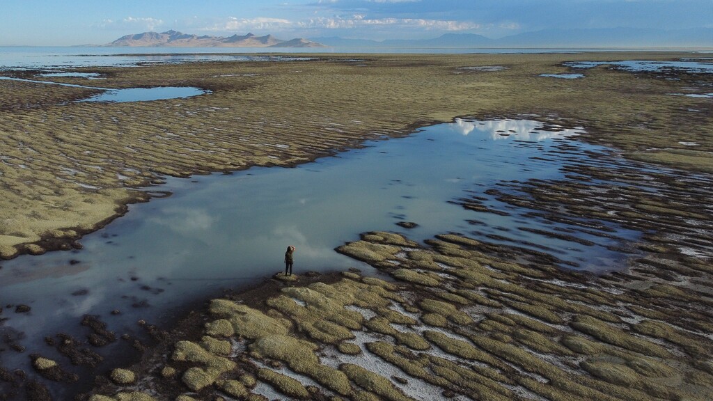 (Rick Bowmer | AP) Angelic Lemmon, a park ranger for Utah's Department of Natural Resources, walks across reef-like structures called microbialites, exposed by receding waters at the Great Salt Lake, on Sept. 28, 2022, near Salt Lake City. Federal officials will more closely monitor the environmental, economic and health impacts of shrinking lakes throughout the drought-stricken West after President Joe Biden on Tuesday, Dec. 27, 2022, signed a law passed through Congress that creates and funds monitoring efforts into lakes including Utah's Great Salt Lake, California's Mono Lake and Oregon's Lake Albert.