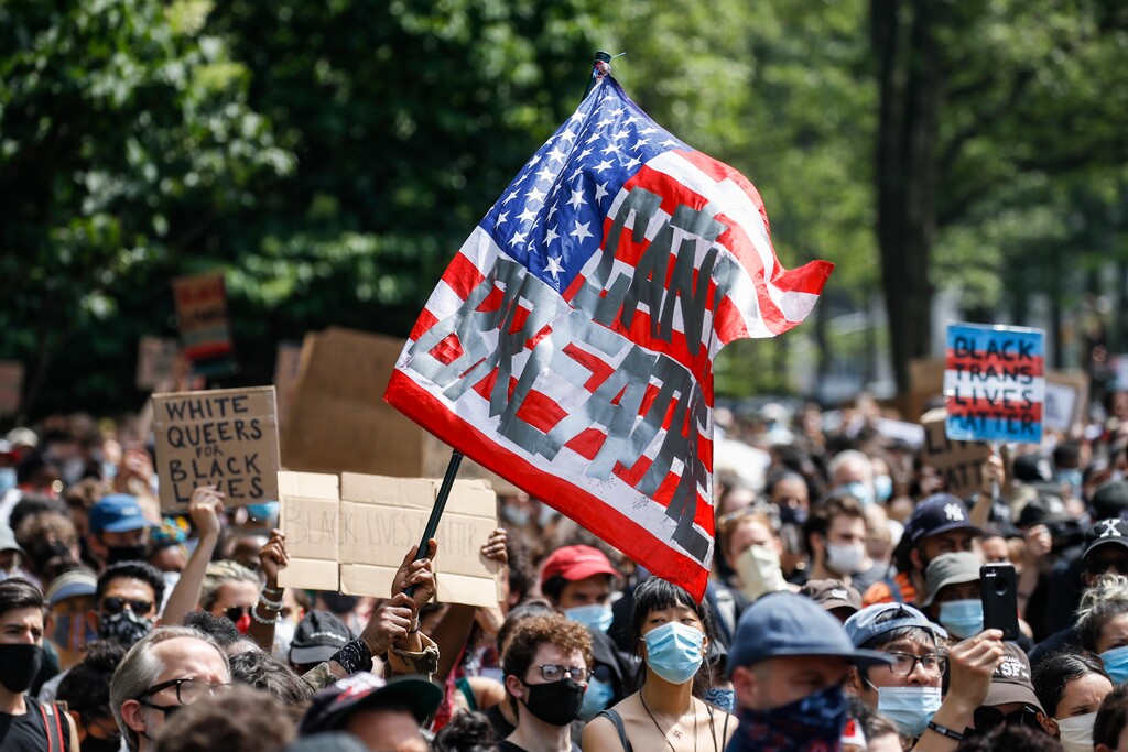 (John Minchillo | AP file photo)  A protester waves an American flag with a message that reads "CAN'T BREATHE" during a memorial for George Floyd at Cadman Plaza Park in the Brooklyn borough of New York, on Thursday, June 4, 2020. Floyd, an African American man, died on May 25 after a white Minneapolis police officer pressed a knee into his neck for several minutes even after he stopped moving and pleading for air.