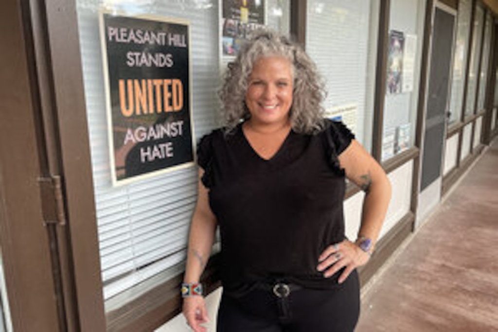 Karen Leslie Hernandez, interim executive director of the Interfaith Council of Contra Costa County, poses with a sign in the window of the Interfaith Council that reads, “Pleasant Hill Stands United Against Hate.”