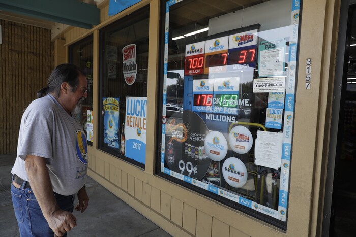 Mike Brum looks at a display advertising lottery tickets for sale Wednesday, Aug. 23, 2017, in Fremont, Calif. Officials estimated jackpot for Wednesday night's Powerball lottery game has climbed to $700 million, making it the second largest in U.S. history. (AP Photo/Marcio Jose Sanchez)