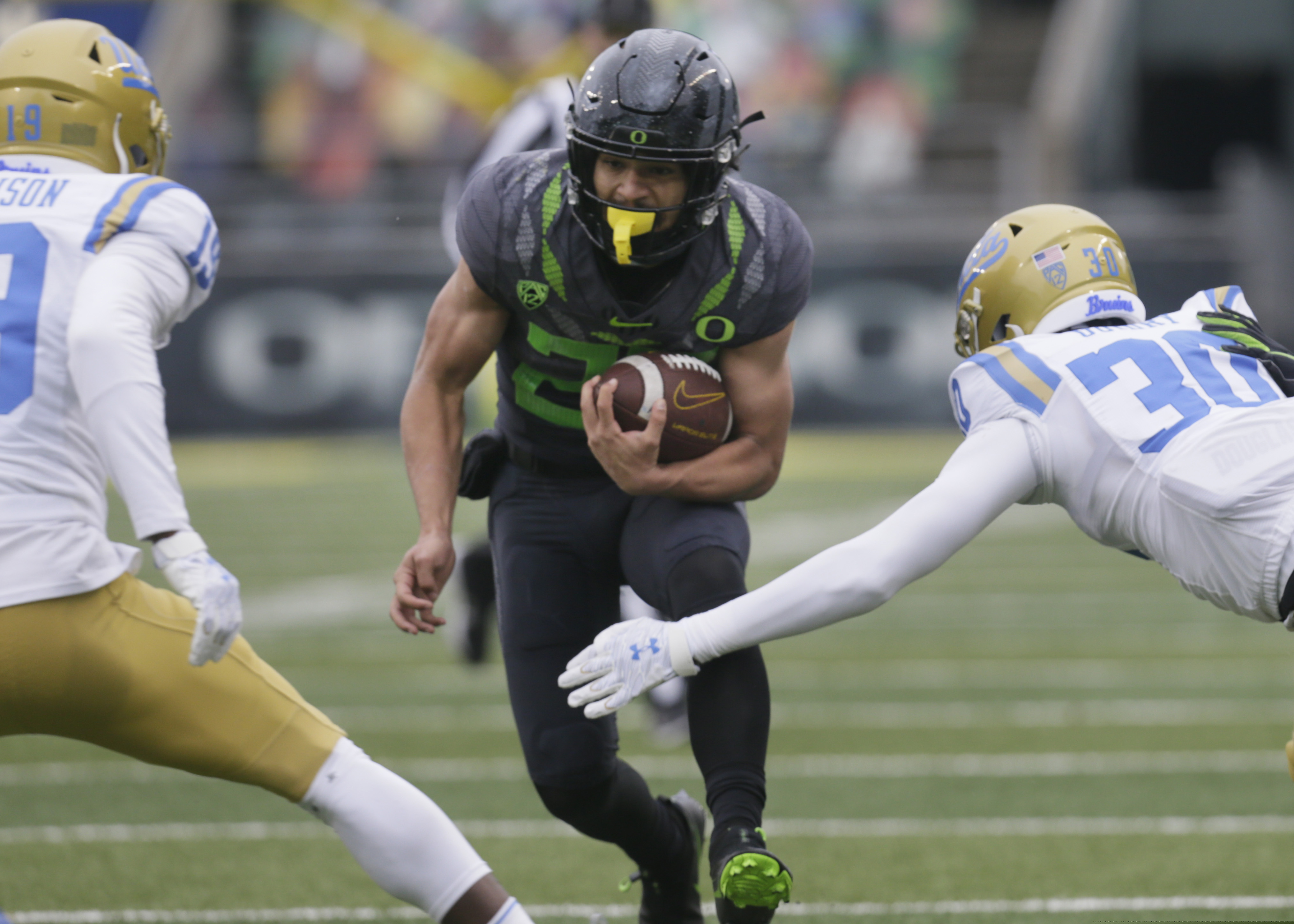 Oregon's Travis Dye, center, rushes against UCLA during the second quarter of an NCAA college football game Saturday, Nov. 21, 2020, in Eugene, Ore. (AP Photo/Chris Pietsch)
