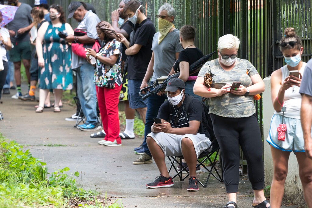 John Bazemore | The Associated Press
Steven Posey checks his phone as he waits in line to vote, Tuesday, June 9, 2020, at Central Park in Atlanta. Voters reported wait times of three hours.