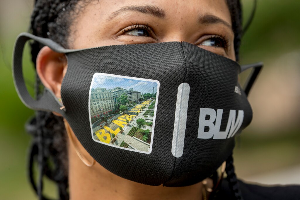 (Andrew Harnik | AP file photo) Shawna Jacobs of Fort Washington, Md., wears a mask with a photograph of 16th Street Northwest renamed Black Lives Matter Plaza near the White House, Friday, June 19, 2020, in Washington.