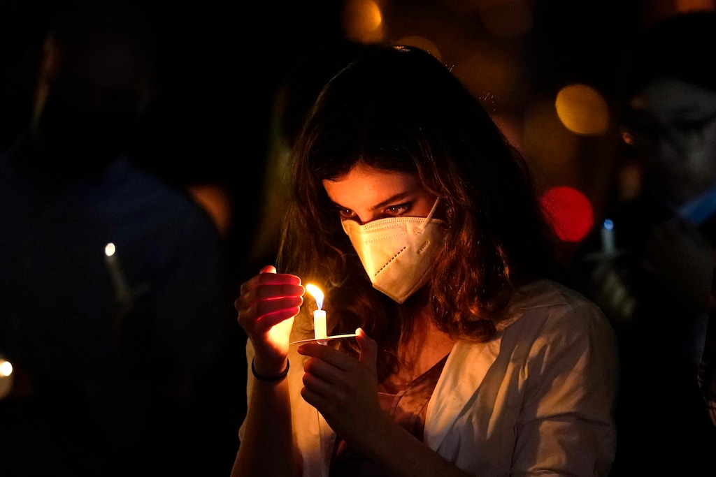 (Lynne Sladky | AP file photo)  A woman wears a protective face mask while holding a candle during an outdoor Christmas Eve Service of Lights at the Granada Presbyterian Church, Thursday, Dec. 24, 2020, in Coral Gables, Fla.