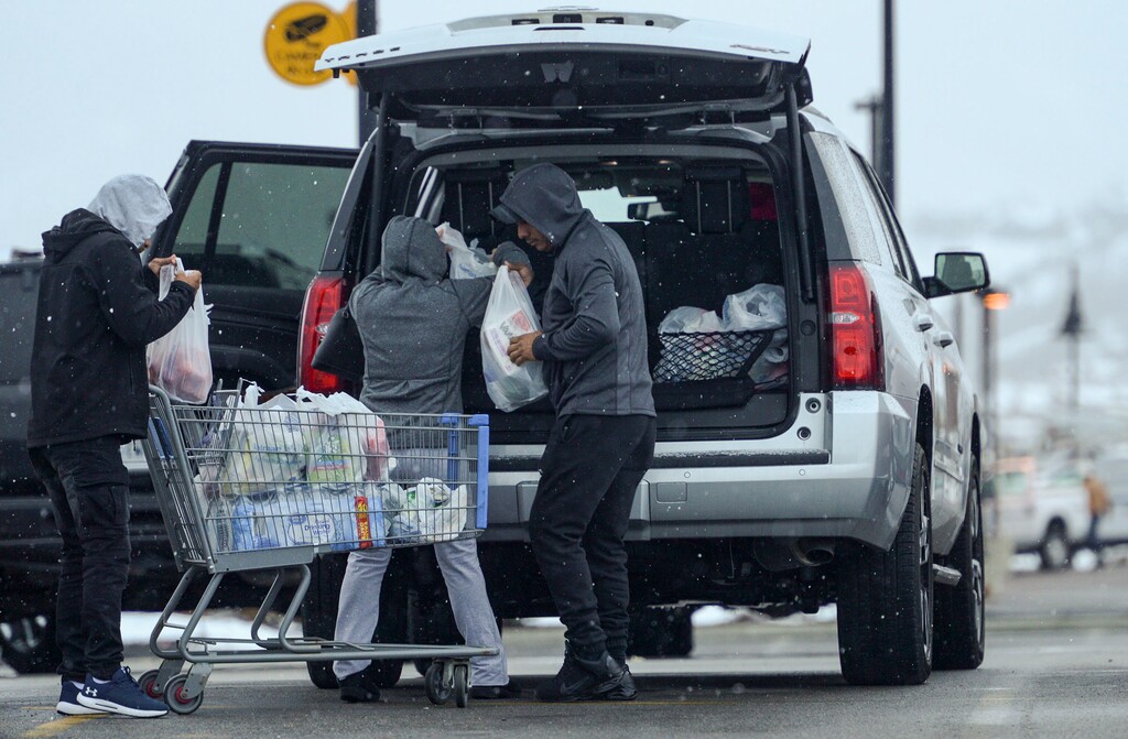 (Leah Hogsten | Tribune file photo) A family loads a cart full of groceries into their car outside of Walmart in Park City, March 25, 2020.