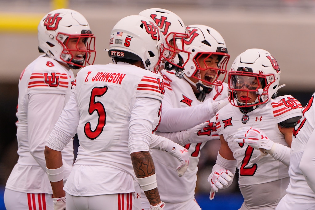 (Charlie Riedel | AP) Utah cornerback Smith Snowden, right, celebrates with teammates after getting an interception during the first half of an NCAA college football game against Kansas, Friday, Nov. 28, 2025, in Lawrence, Kan.